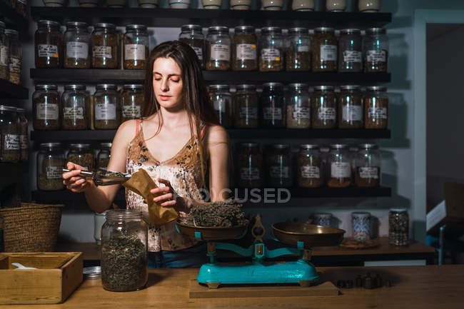 Woman putting spices to bag in shop — Stock Photo