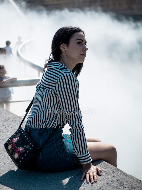 Chica en la cerca en la niebla de agua - foto de stock