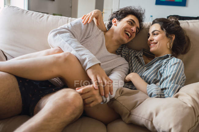Веселая молодая пара веселится на диване — стоковое фото
