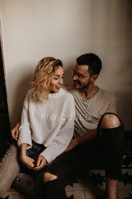 Sorrindo homem e mulher sentados no chão em casa juntos — Fotografia de Stock