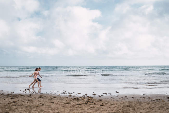 Junge und Mädchen spazieren im Sommer am Strand — Stockfoto