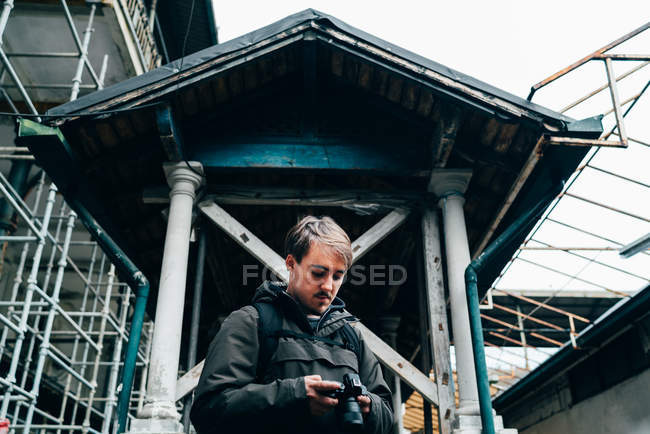 Uomo in piedi e utilizzando la fotocamera di fronte al vecchio edificio squallido — Foto stock