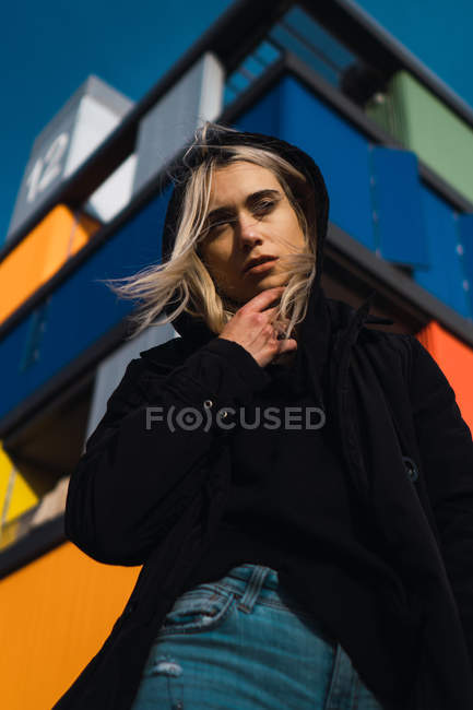 Приваблива блондинка дивиться на камеру проти барвистої будівлі — стокове фото