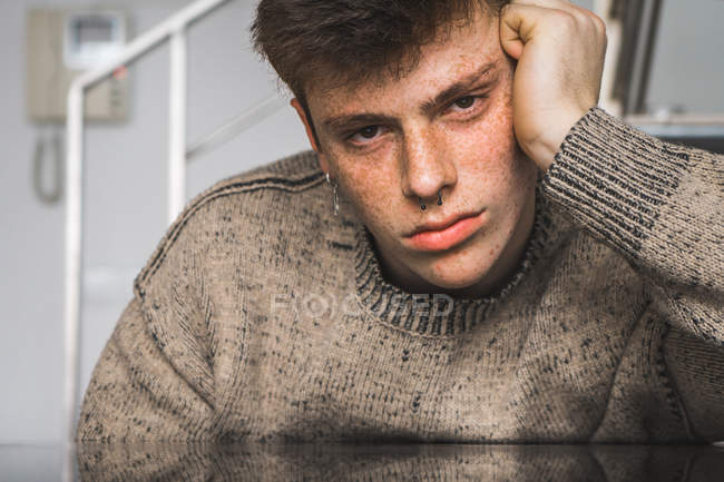 Freckled man in sweater holding head and looking at camera — Stock Photo