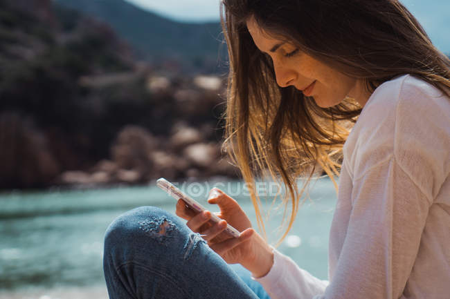 Frau benutzt Smartphone in Felsen am Meer — Stockfoto