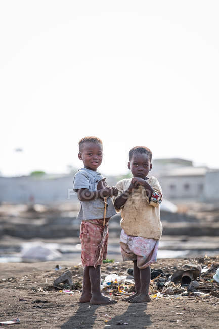 ANGOLA - AFRICA - 5 APRILE 2018 - Due ragazzi in piedi davanti alla pila dell'immondizia e guardando la telecamera nel villaggio — Foto stock