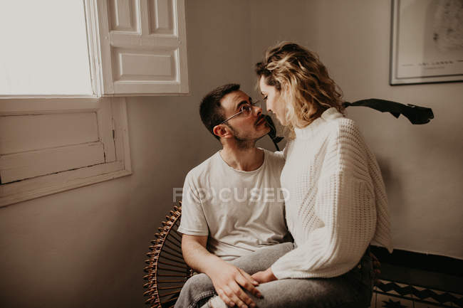 Casal feliz sentado em poltrona e olhando um para o outro enquanto se unem em casa — Fotografia de Stock