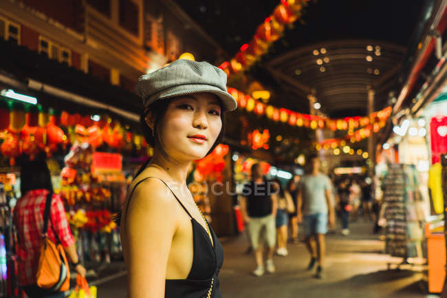 Portrait of young Asian woman in stylish clothes standing on street at night — Stock Photo