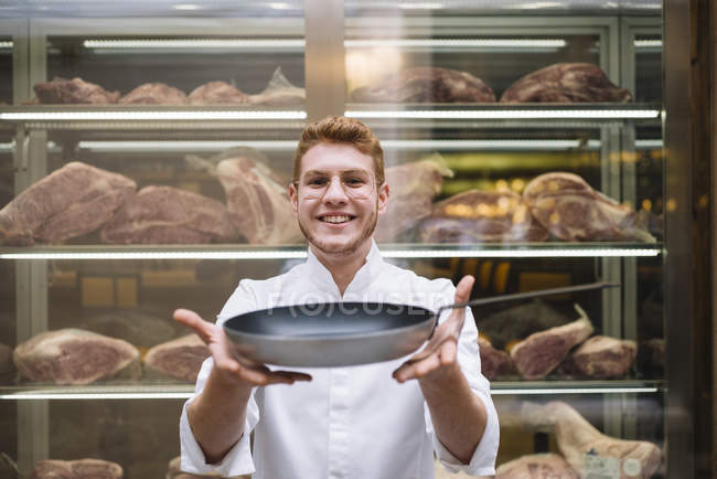 Портрет шеф-кухаря в окулярах і білій сукні, що показує ресторан на сковороді — стокове фото