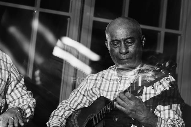 Музикант грає на гітарі в нічному клубі, чорно-білий постріл з тривалою експозицією — стокове фото