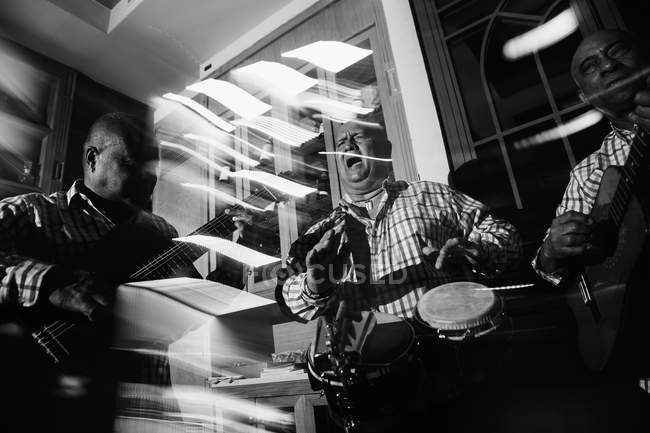 Кубинское музыкальное трио, выступающее в ночном клубе, черно-белый кадр с длительной экспозицией — стоковое фото
