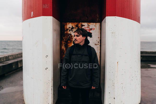 Thoughtful man standing at grungy door of red and white building on coast, Porto, Portugal — Stock Photo