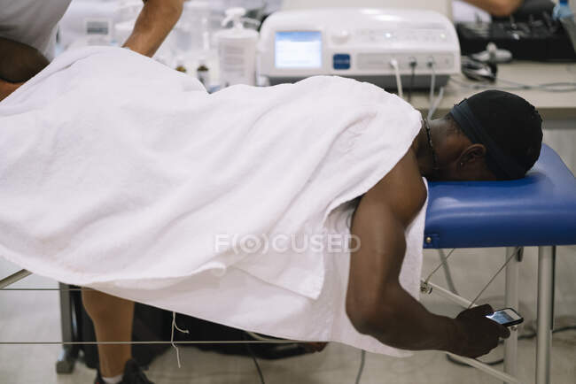 Der Physiotherapeut, der einen Mann behandelt, der Geräte für die Strahlentherapie benutzt — Stockfoto