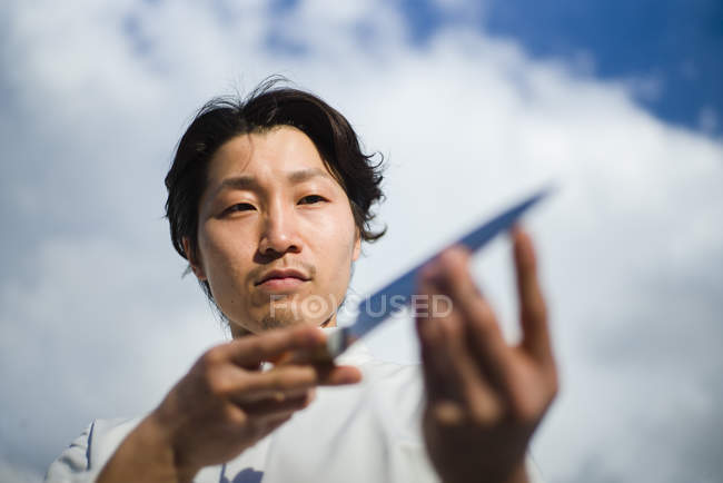 Chef japonês verificando faca na frente do céu azul — Fotografia de Stock