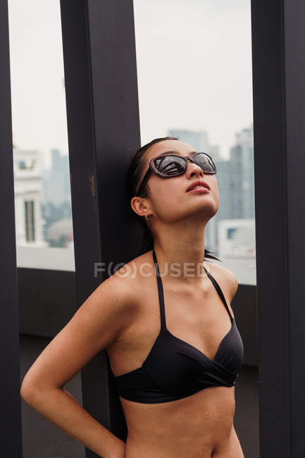 Thoughtful woman in swimsuit leaning on wall — Stock Photo