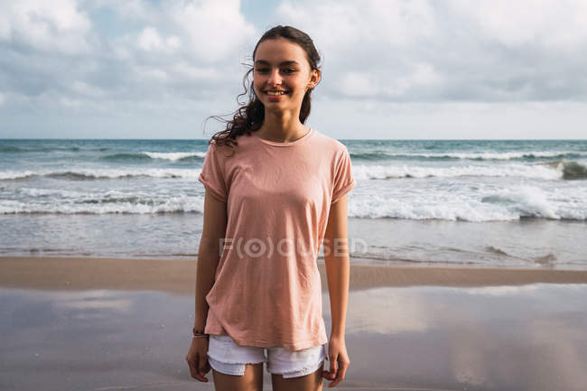 Portrait of smiling teen girl standing on beach — Stock Photo