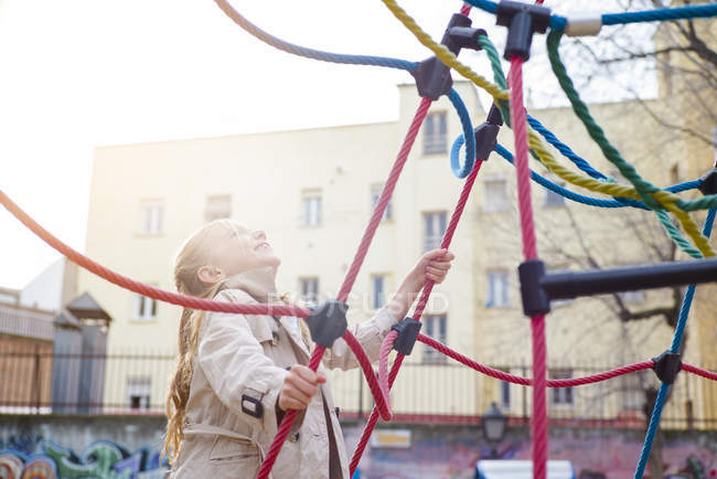 Menina loira alegre olhando para cima no parque infantil — Fotografia de Stock