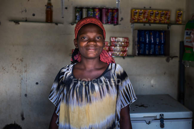 ANGOLA - ÁFRICA - 5 de abril de 2018 - retrato de una mujer negra que trabaja en una tienda de pueblo y mira a la cámara - foto de stock