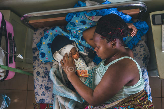 КАМЕРУН - Африка - 5 апреля 2018 года: этническая женщина и маленький ребенок лежат на кровати в больнице — стоковое фото