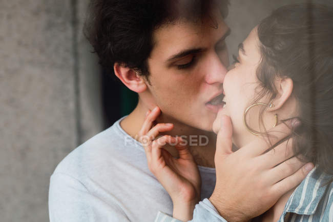 Sensual joven pareja besándose detrás de ventana - foto de stock