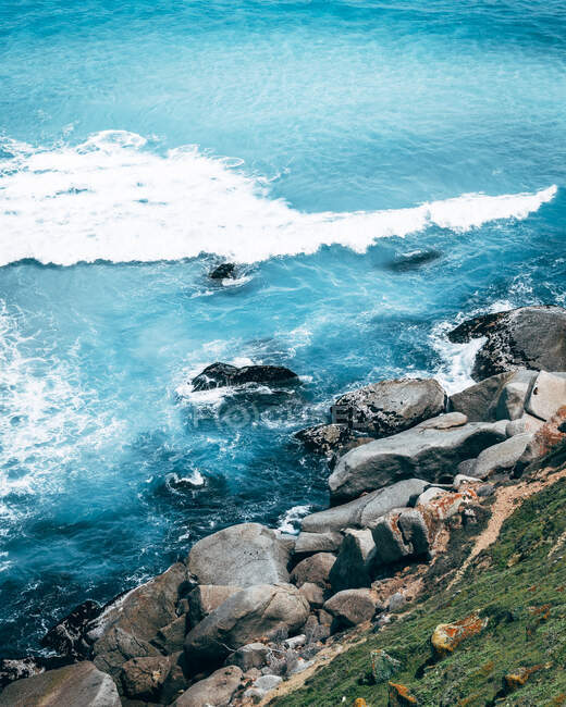 Von oben Sandküste mit Felsen und blauem Meer in sonnigem Tag. — Stockfoto
