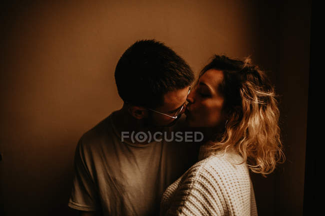 Cariñosa joven pareja besándose en la pared - foto de stock