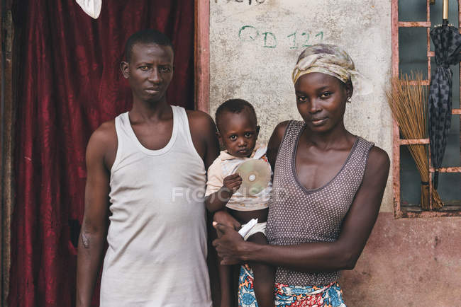 КАМЕРУН - Африка - 5 апреля 2018 года: Взрослые африканские мужчина и женщина с ребенком на руках стоят перед камерой и смотрят на нее — стоковое фото