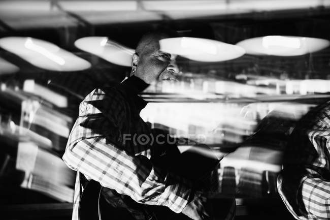 Музыкант играет на гитаре в ночном клубе, черно-белый кадр с длительной экспозицией — стоковое фото