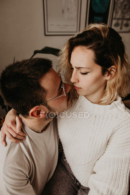 Romantic man and woman sitting and embracing at home together — Stock Photo