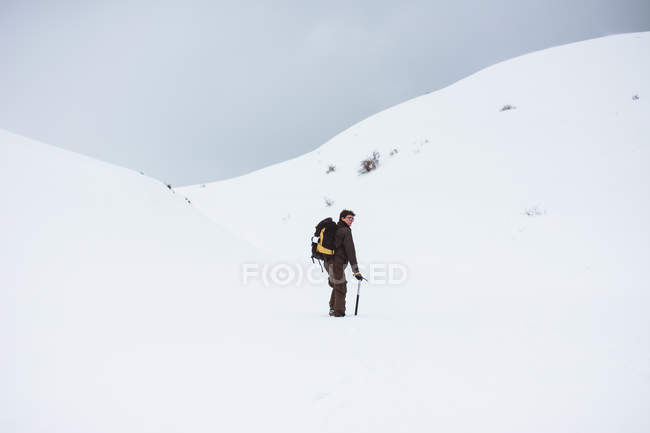 Turista com mochila subindo na montanha nevada — Fotografia de Stock