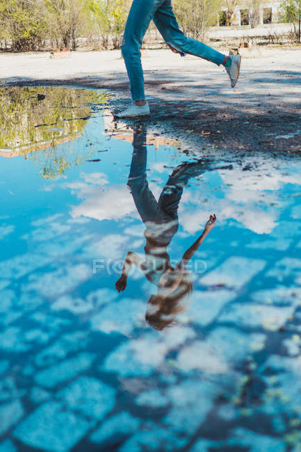 Menina pulando acima da poça com reflexão — Fotografia de Stock