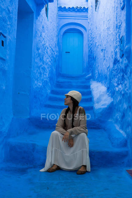 Вдумчивая женщина сидит на лестнице в марокканском городе окрашенный синий — стоковое фото