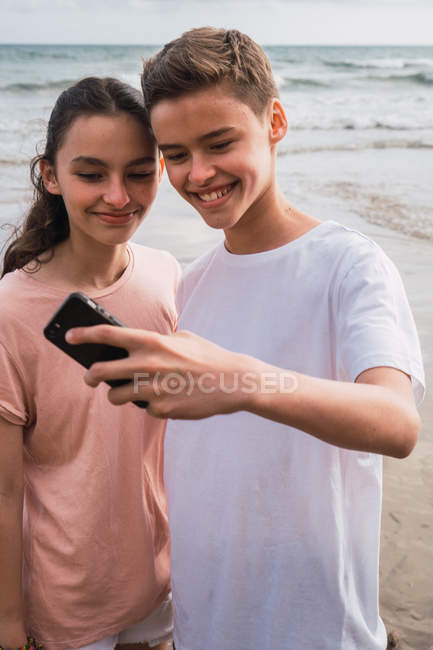 Dos adolescentes sonrientes tomando selfie en la orilla del mar - foto de stock