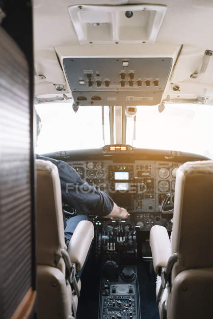 Homme méconnaissable dans un casque pilotant un avion assis dans le cockpit d'un avion moderne — Photo de stock