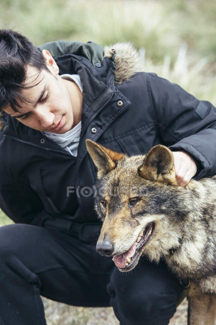 Junger Mann streichelt Wolf im Zoo — Stockfoto