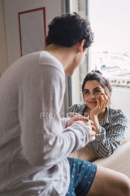 Couple avec des tasses parlant dans le salon — Photo de stock