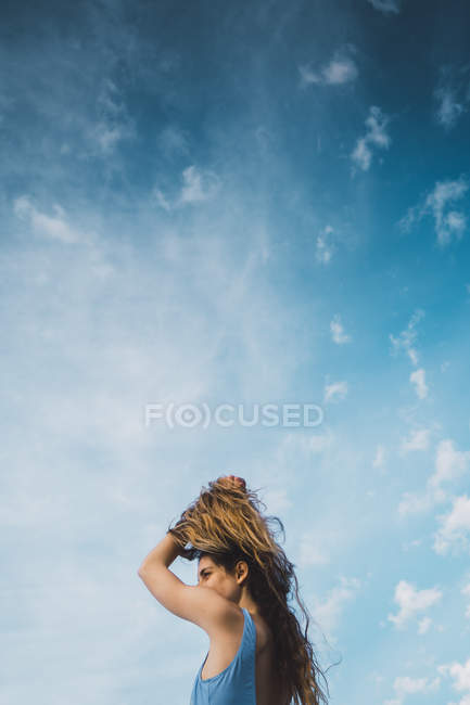 Femme joyeuse en maillot de bain bleu debout contre le ciel bleu — Photo de stock