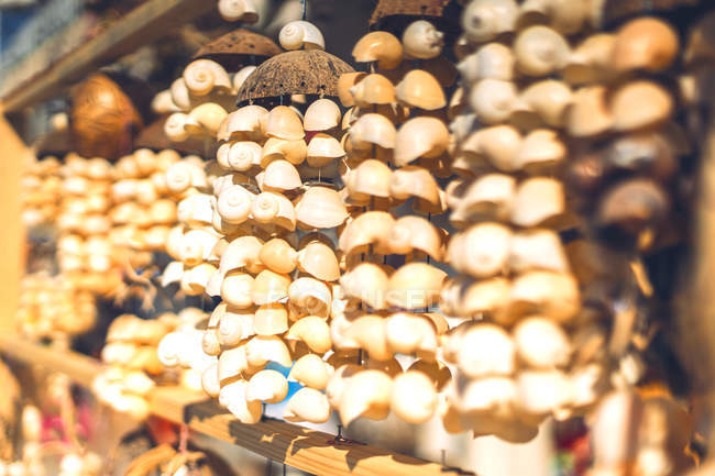 Un mucchio di decorazioni di conchiglie appese alla bancarella al mercato — Foto stock