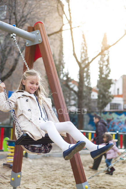 Усміхнена блондинка гойдається в парку — стокове фото