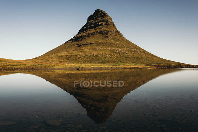 View to big mountains reflecting in the calm ocean in cloudless day. — Stock Photo