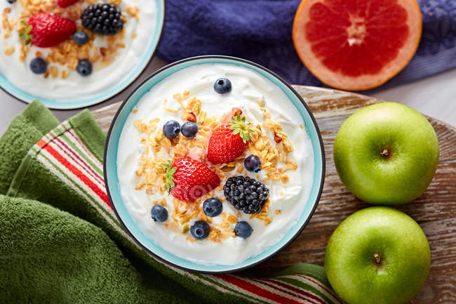 Bowl of fresh yogurt topped with berries and cornflakes on board — Stock Photo