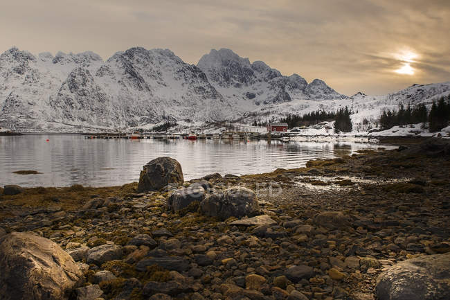 Bucht und felsige Berge mit Schnee bedeckt unter bewölktem Himmel, hamnoy, Norwegen — Stockfoto