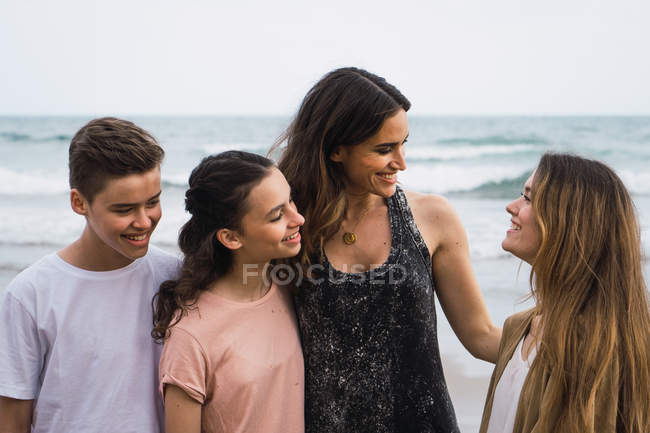 Portrait of woman and teenagers standing and talking on seashore — Stock Photo