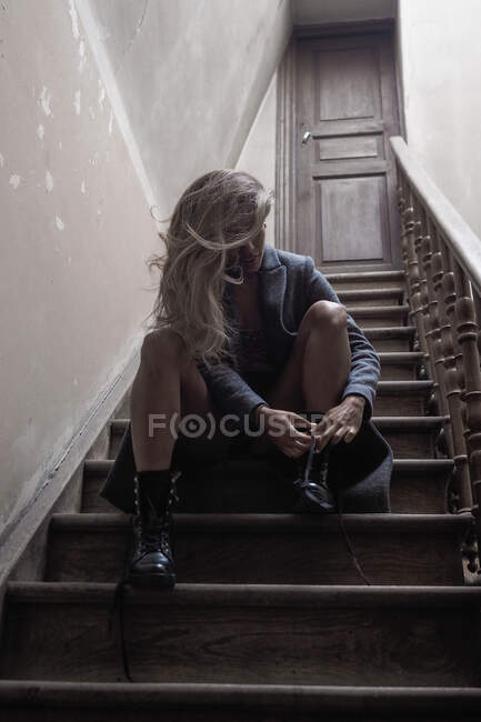 Trendy girl tying shoelaces on stairs — Stock Photo