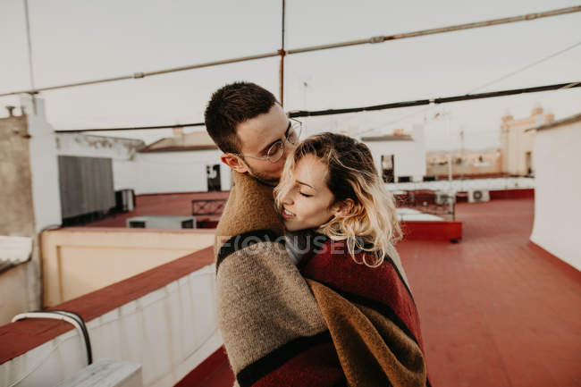 Coppia abbracci con coperta sulla terrazza — Foto stock
