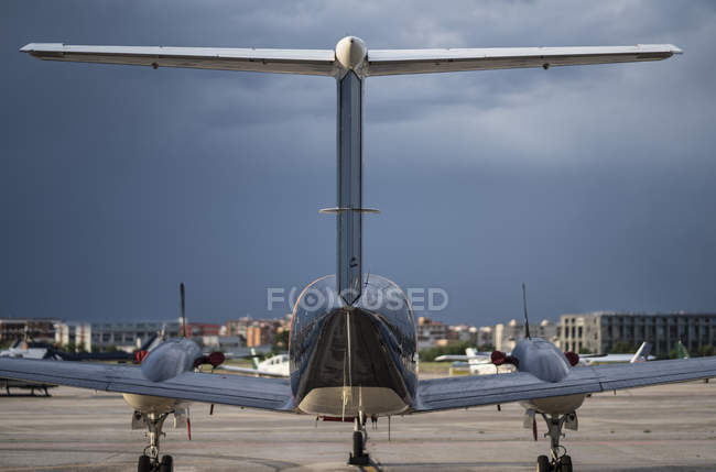 Aeronaves em pé no solo do aeródromo civil na cidade contra o céu nublado — Fotografia de Stock