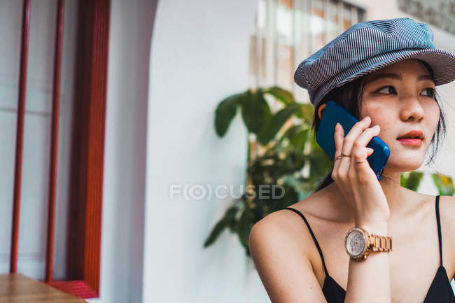 Jovem mulher asiática em pé na frente da construção e falando no smartphone — Fotografia de Stock