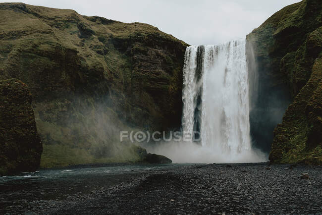 Vue sur une grande cascade qui coule de la montagne verte dans la nature. — Photo de stock