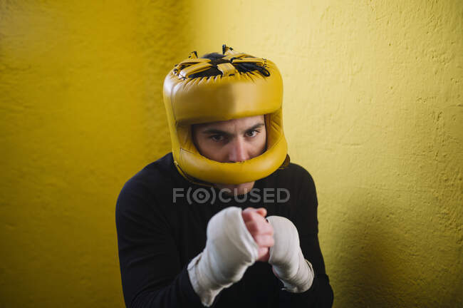 Confident fighter man with bandaged arms in helmet looking at camera. — Stock Photo