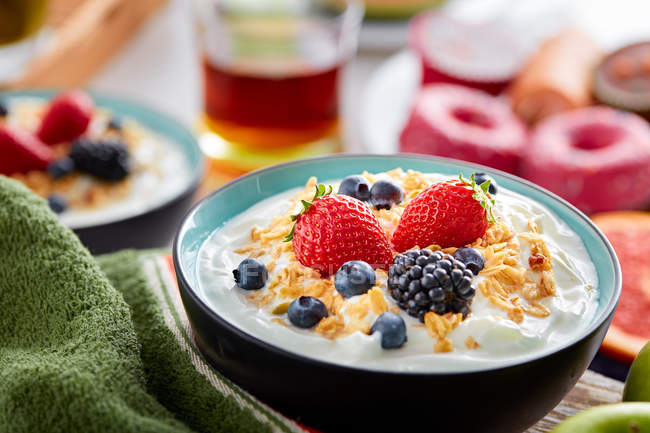 Bowl of fresh yogurt topped with berries and cornflakes — Stock Photo